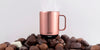 Ember Mug² in Rose Gold sitting on a pile of assorted chocolates.