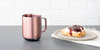Ember Mug² in Rose Gold on a slate gray countertop next to a cream and jam covered pastry.